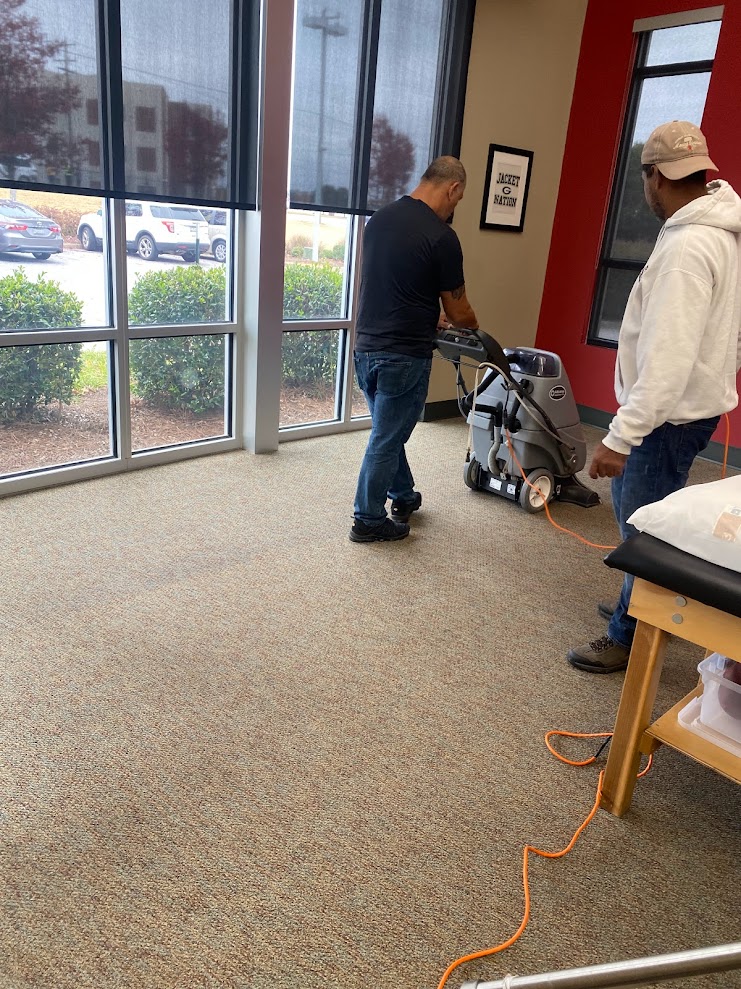 Professional carpet cleaning technicians using commercial extraction equipment in modern office